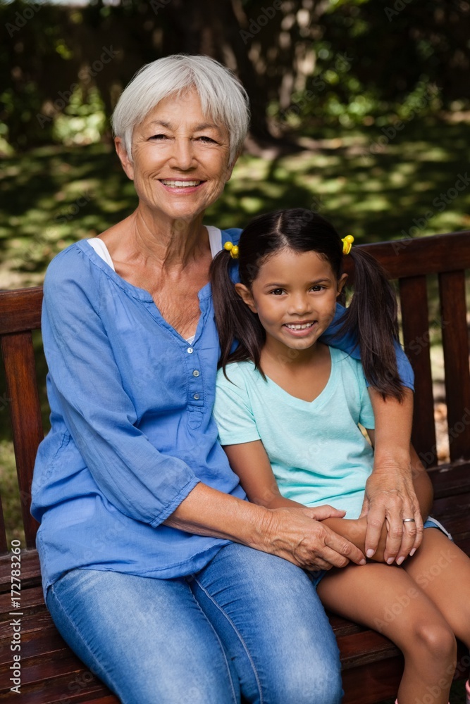Portrait of granddaughter and senior woman sitting on wooden Portrait of granddaughter and senior woman sitting on wooden