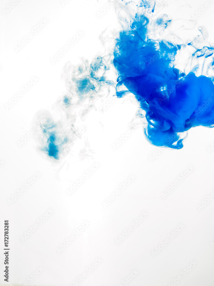 Ink swirl in water isolated on white background. The paint in the water. Soft dissemination a droplets of blue ink in water close-up. Abstract background. Soft focus.