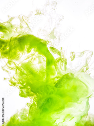 Ink swirl in water isolated on white background. The paint in the water. Soft dissemination a droplets of green ink in water close-up. Abstract background. Soft focus.