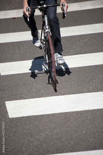 Fototapeta Naklejka Na Ścianę i Meble -  Cyclist crosses the road on pedestrian crossing marked with zebra crossing