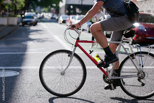 Cyclist running on across the sunny street of modern city