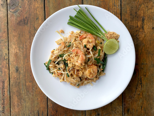 Pad Thai, stir-fried rice noodles with shrimp in white plate on wood table. The one of Thailand's national main dish. the popular food in Thailand. Thai Fried Noodles