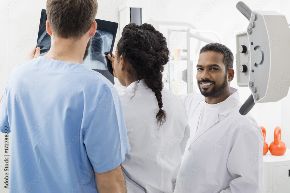 Radiologist With Colleagues Analyzing X-ray In Hospital Radiologist With Colleagues Analyzing X-ray In Hospital