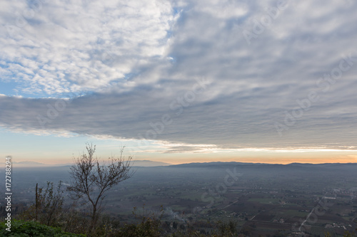 A n aerial view of Umbria valley at sunset, with very low clouds and warm colors