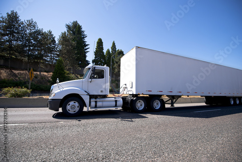 White big rig day cab semi truck and dry van trailer for local delivery and reposition of industrial cargo photo