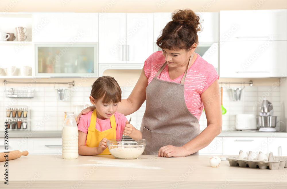 Cute little girl and her grandmother making dough on kitchen Cute little girl and her grandmother making dough on kitchen