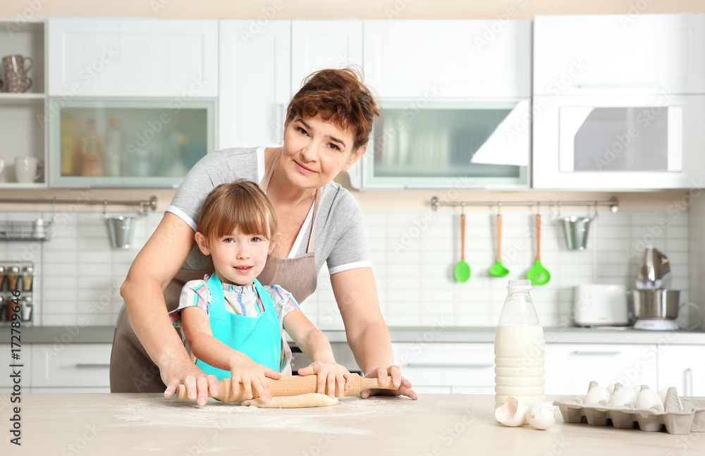 Cute little girl and her grandmother on kitchen Cute little girl and her grandmother on kitchen