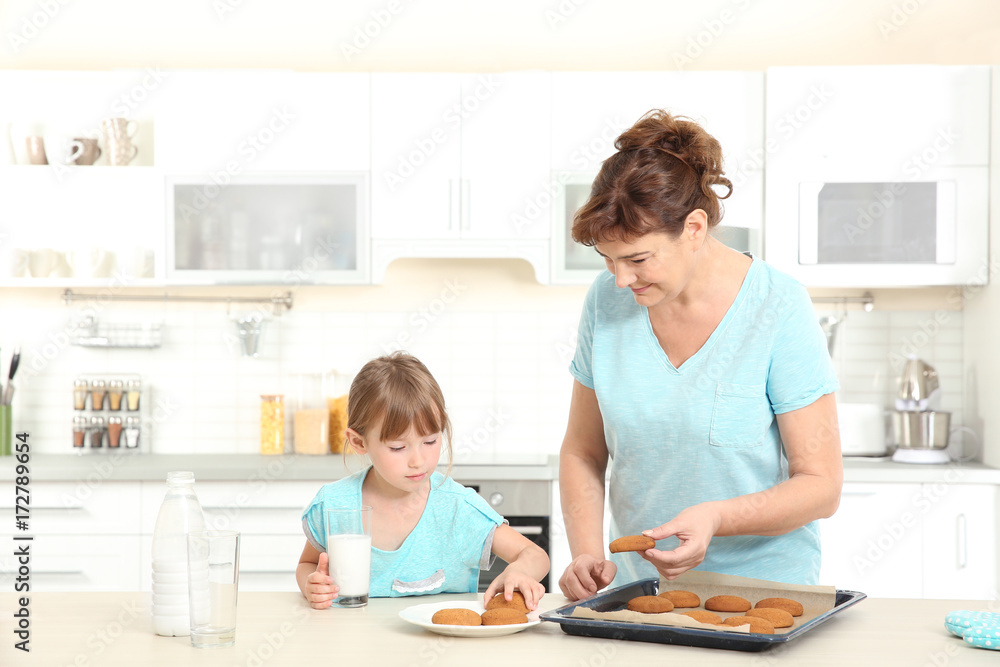 Cute little girl and her grandmother tasting cookies on kitchen Cute little girl and her grandmother tasting cookies on kitchen