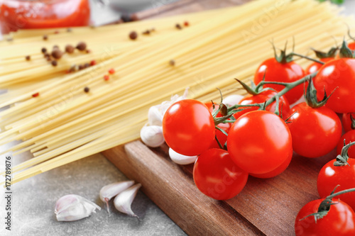 Tasty tomatoes and pasta on wooden board