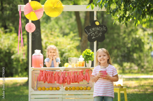 Adorable little girl with jar near lemonade stand in park