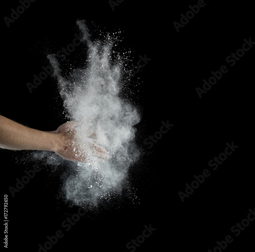 Freeze motion of dust explosion in hands isolated on black background photo