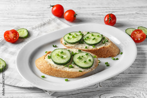 Plate of tasty sandwiches with fresh cucumber on table