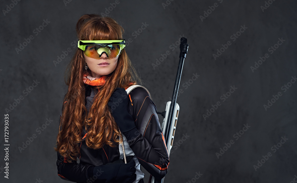 Fototapeta premium Redhead Biatlon female sportsmen holds competitive gun.