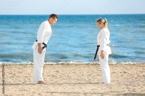Young man and woman performing ritual bow prior to practicing karate outdoors