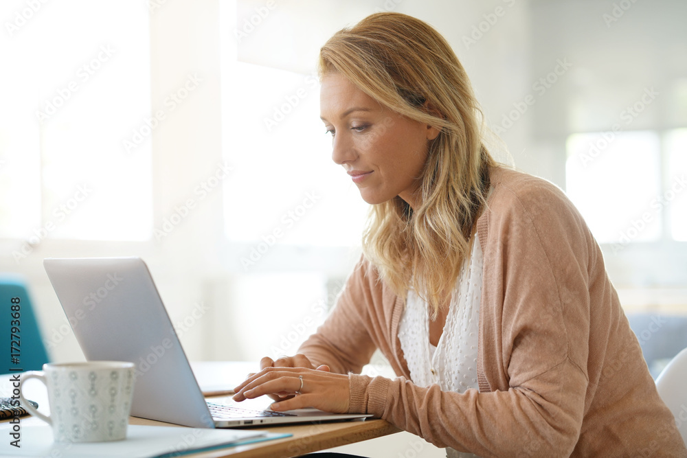 Attractive blond woman working on laptop computer at home Attractive blond woman working on laptop computer at home