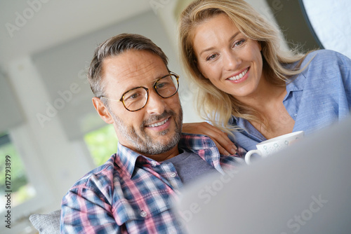 Mature couple connected on internet with laptop photo