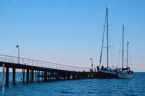 Evening sunset, old pier and two yachts