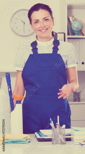 Cheerful female cleaning furniture in office photo