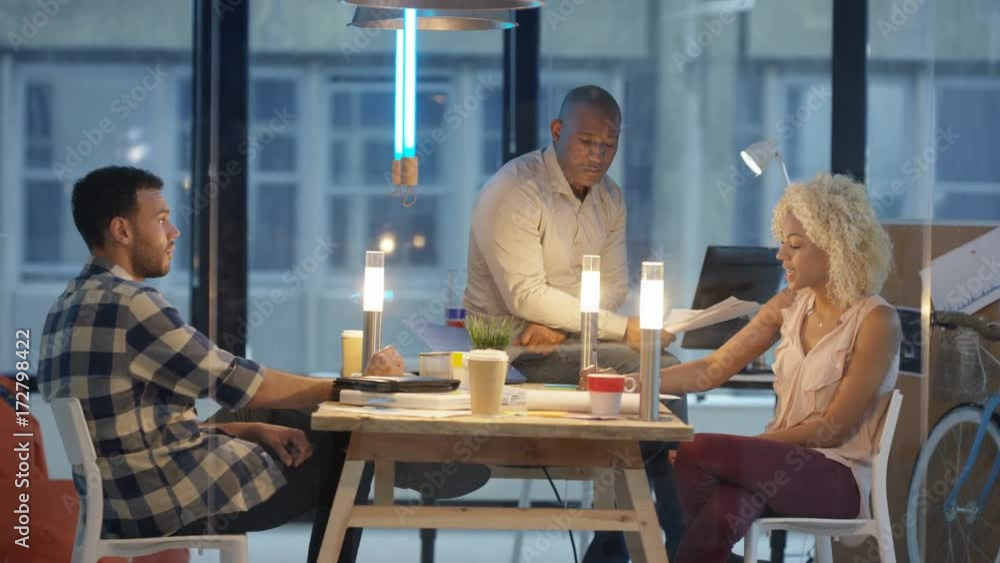 Cheerful casual business team planning and looking over the figures in modern office. Partners in young startup company discussing business plan. Cheerful casual business team planning and looking over the figures in modern office. Partners in young startup company discussing business plan.
