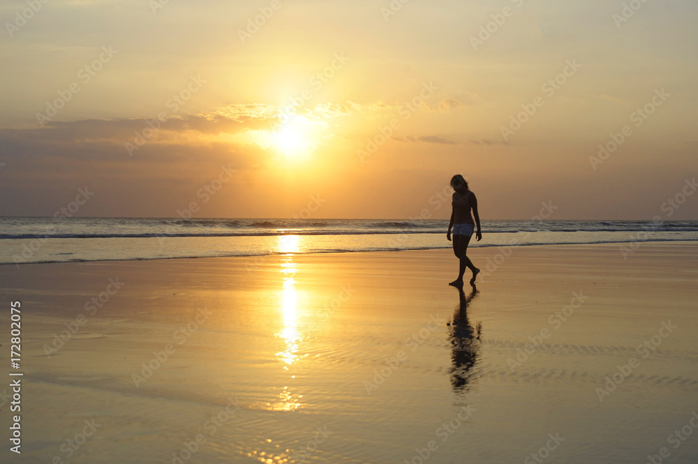 asian young woman walking peacefully on desert beach on sunset in meditation and freedom concept