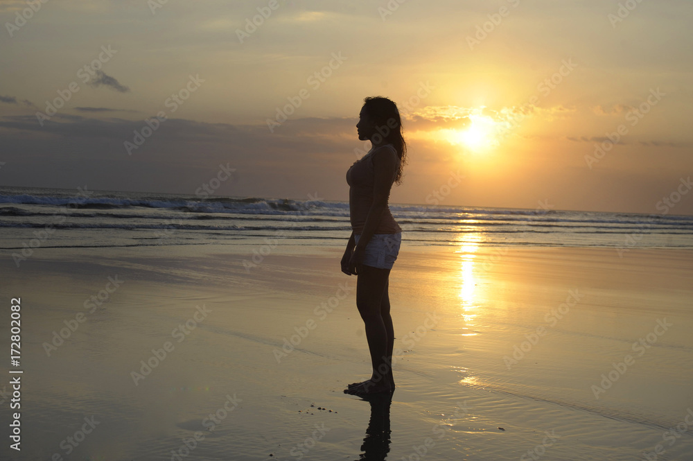 woman meditating and thinking peacefully on desert beach on sunset in meditation and freedom