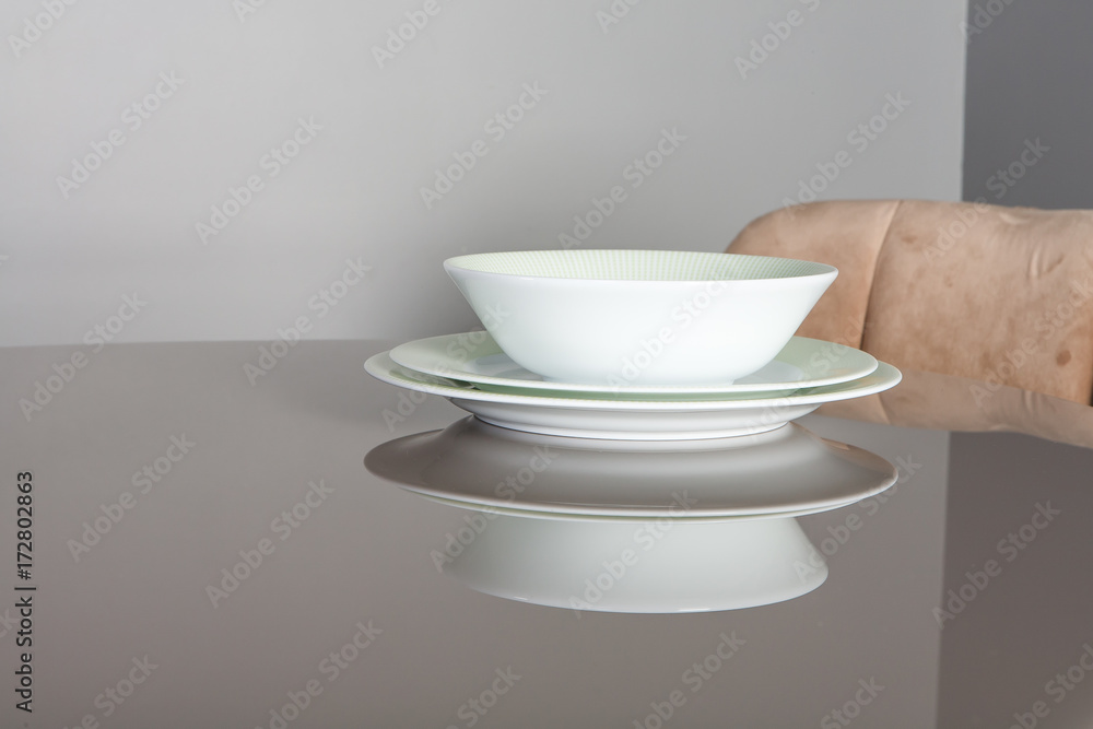 Beautiful empty plates with the green rim on the mirror table Beautiful empty plates with the green rim on the mirror table