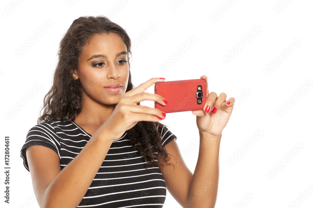 Young and happy dark skinned girl taking photos with her smartphone Young and happy dark skinned girl taking photos with her smartphone