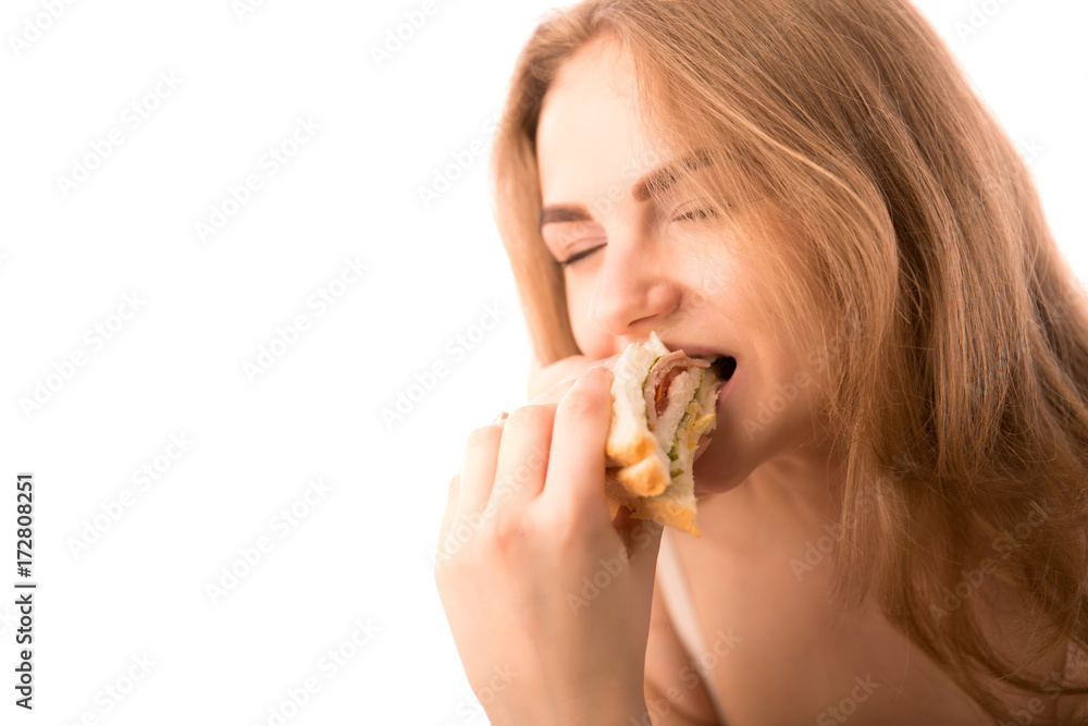 Young woman keeps in hand and eats sandwich with pleasure Young woman keeps in hand and eats sandwich with pleasure