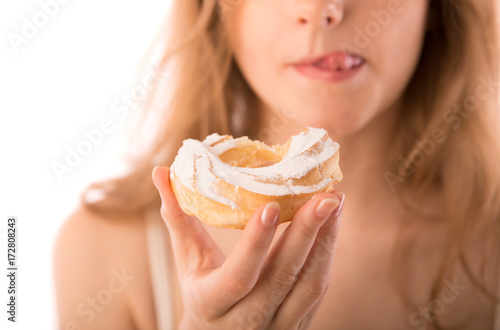 Young woman keeps in hand and eats cake with pleasure