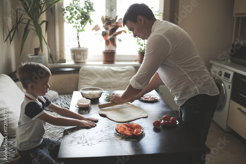 Foto son and father cooking together, cozy real kitchen