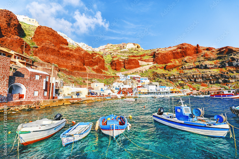 Old port in Oia - Ia village on Santorini volcano island in Cyclades  archipelago in Greece, European country. Fishing boats at foreground,  ginger rocks in background. Santorini is popular resort. Photos