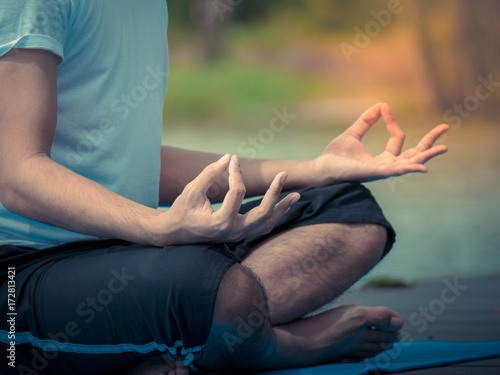 The acting setup of Yoga concept. A asian young man doing Yoga outdoor by the lake.