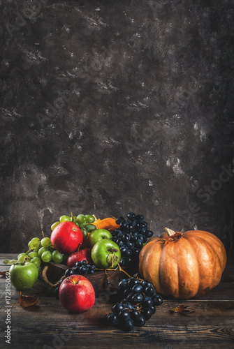 Autumn and thanksgiving harvest concept. Seasonal fall fruits and pumpkin on wooden table, copy space