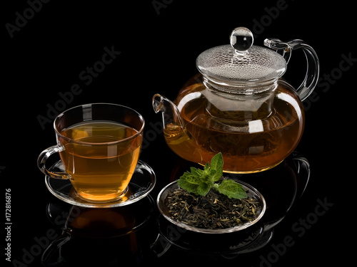 Tea leaves of green tea with petals of fresh mint and a tea drink in glassware