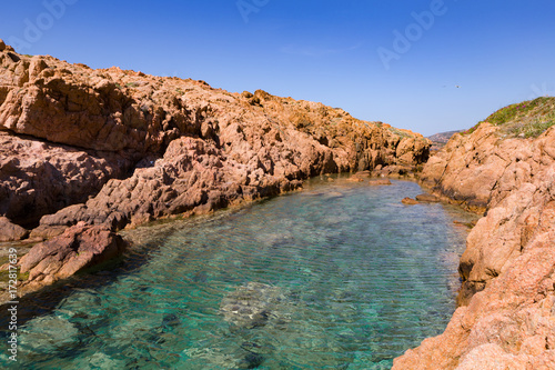 colorful rocky inlet on the coast with red rocks and turquoise water