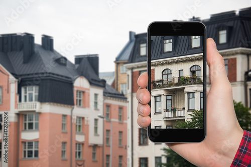 Hand with a phone in the background of a building