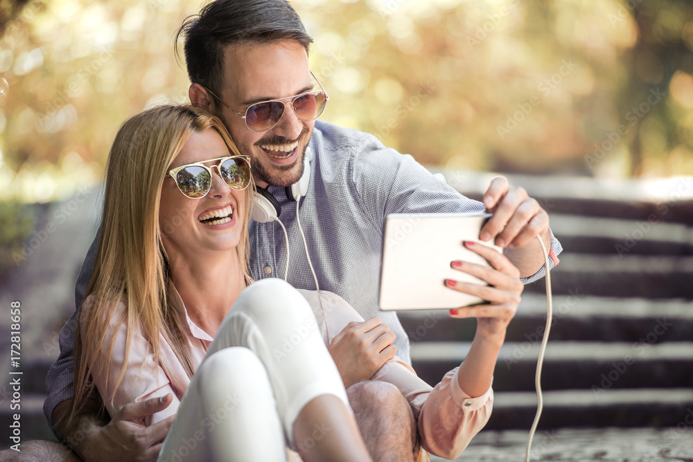 Young loving couple sitting and looking tablet. Young loving couple sitting and looking tablet.