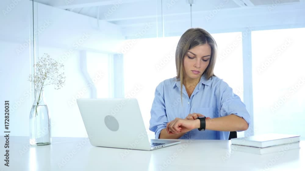 Young Woman Using Smartwatch, Sitting in Office Young Woman Using Smartwatch, Sitting in Office