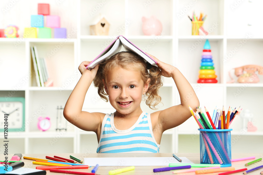 Little girl sitting with book at the table Little girl sitting with book at the table