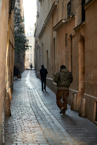 two people walking on a narrow street in old town