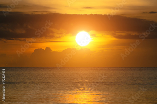 Fototapeta Naklejka Na Ścianę i Meble -  The sun shines through the clouds at dawn on the shore of the Gulf of Thailand.