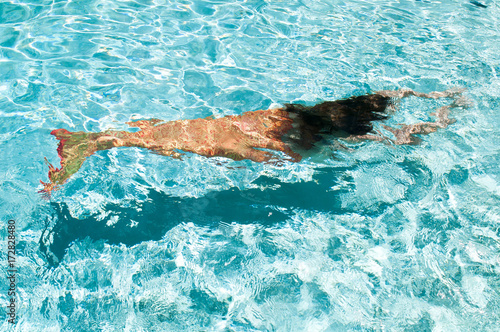 A mermaid with and orange tail underwater.