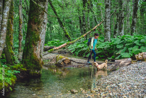 Woman with a dog hiking in the forest