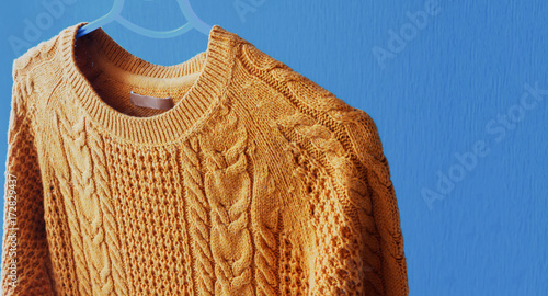 Warm woolen sweater hanging on hanger photo