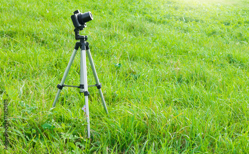 Camera and tripod stand on the grass. Nature photography, camera on tripod with remote in a field.