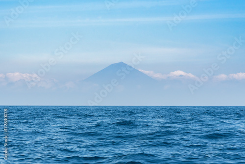 Blue ocean with clear sky and Agung mountain on background. Bali, Indonesia.