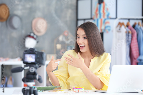 Young female blogger with accessories recording video at home