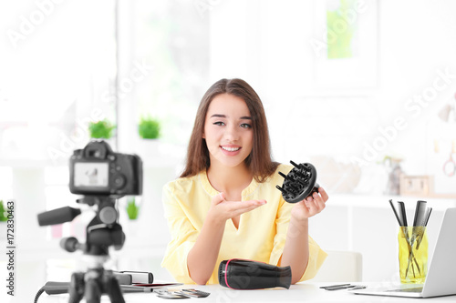 Young female blogger with diffuser recording video at home