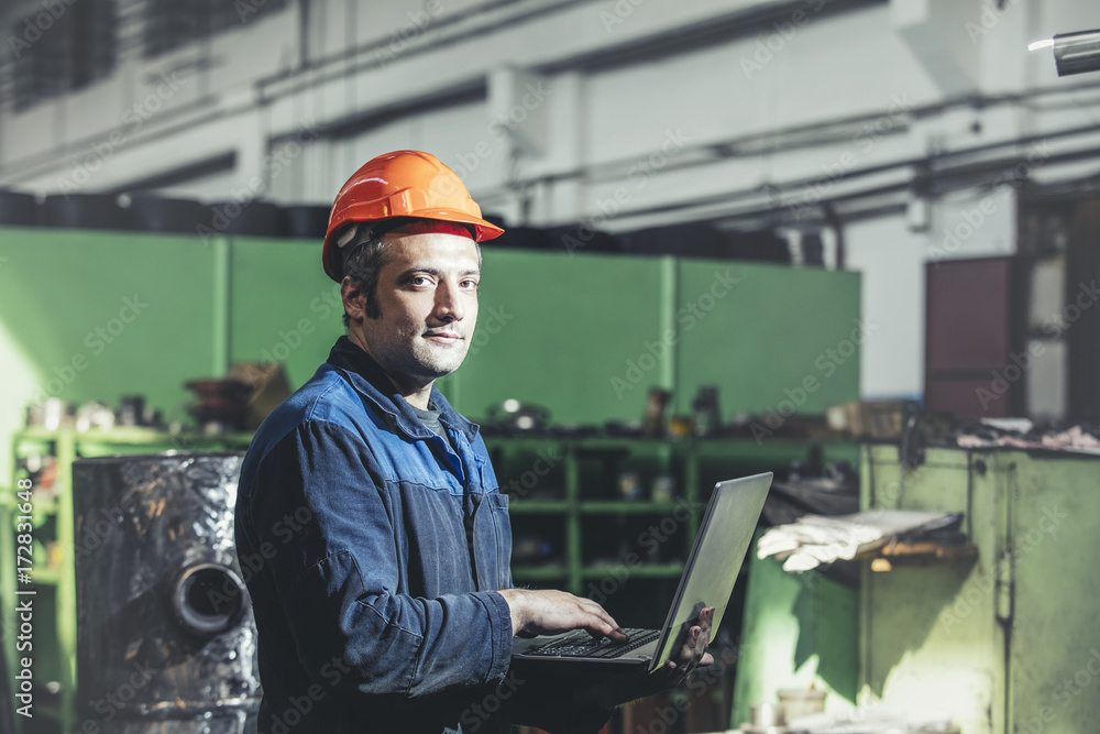 Working in the plant with a laptop in hand on the background of the equipment Working in the plant with a laptop in hand on the background of the equipment