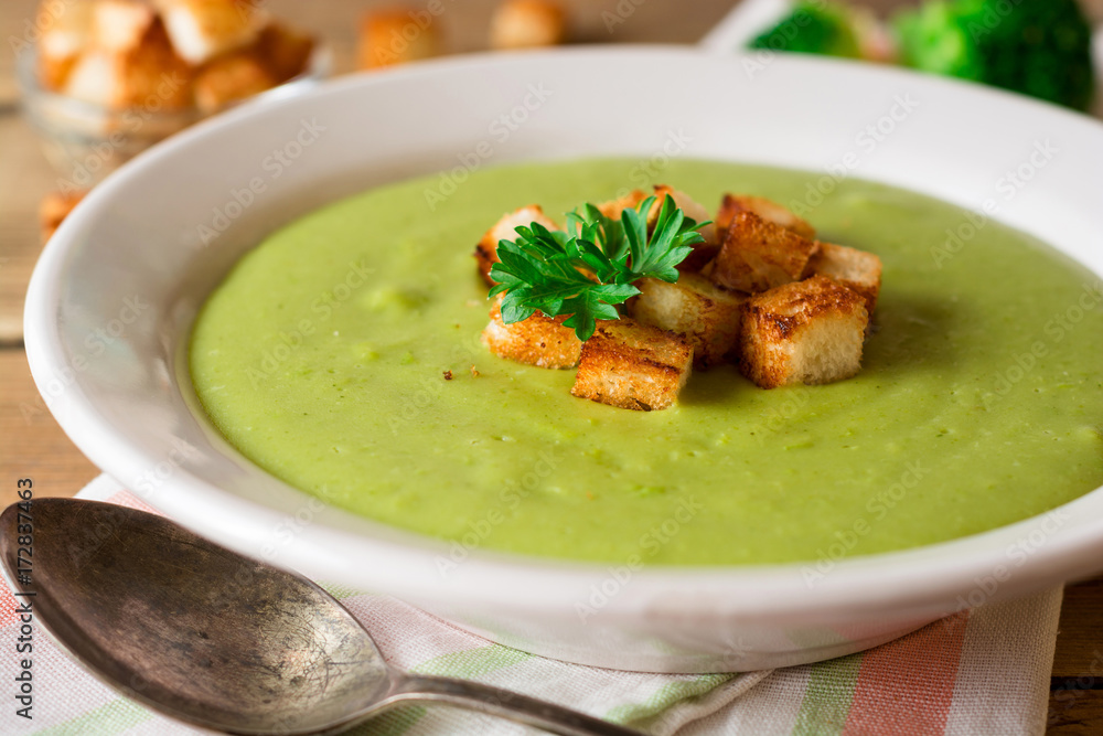 Broccoli cream soup with croutons in plate on rustic wooden table Broccoli cream soup with croutons in plate on rustic wooden table